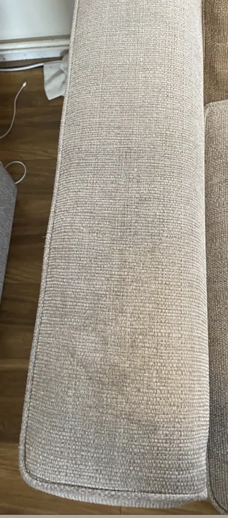 Textured sofa arm before cleaning, visibly soiled